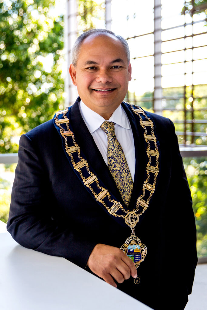Mayor Tom Tate wearing the Chain of Office and a gold tie to match with green garden in the background